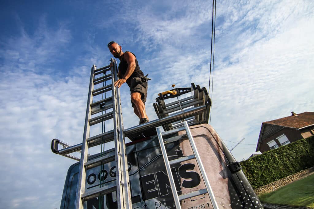 ouvrier qui décharge une échelle d'une camionnette