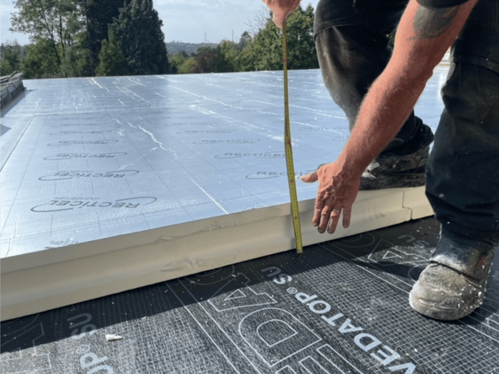 Un ouvrier mesurant de l'isolation pour un toit plat