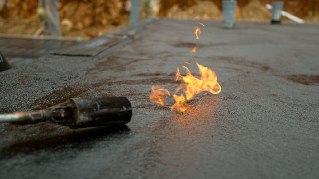 chalumeau brûlant fait fondre lentement le goudron