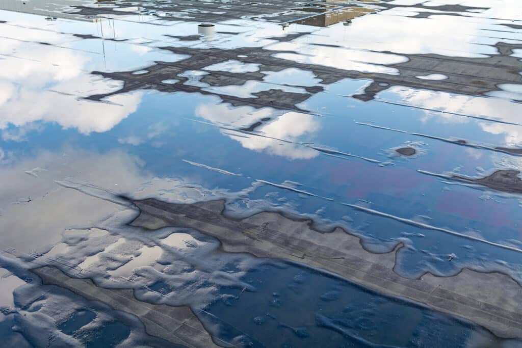 Toit plat avec eau stagnante et reflet du paysage nuageux